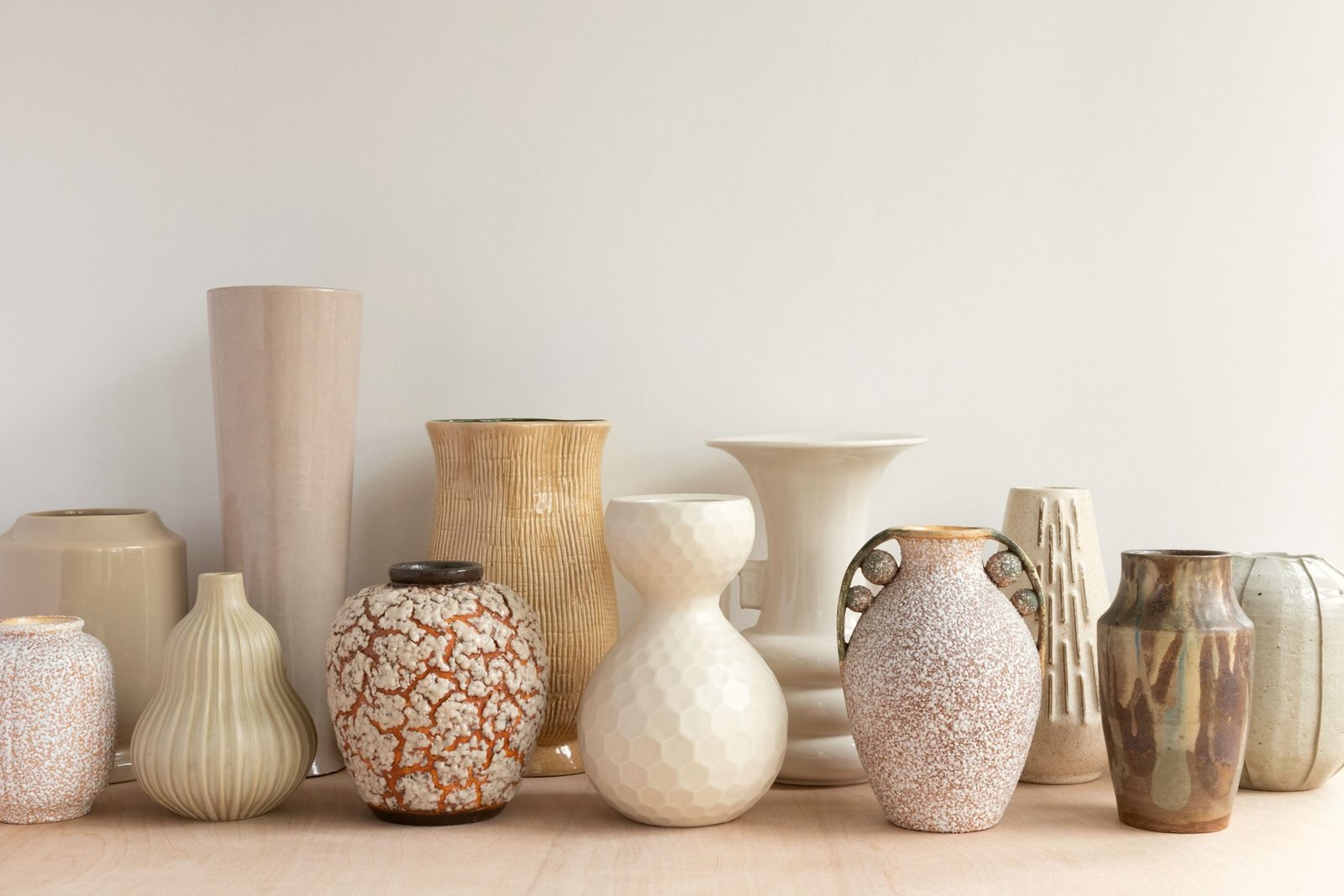 A collection of ceramic vessels in cream, sand and brown glazes