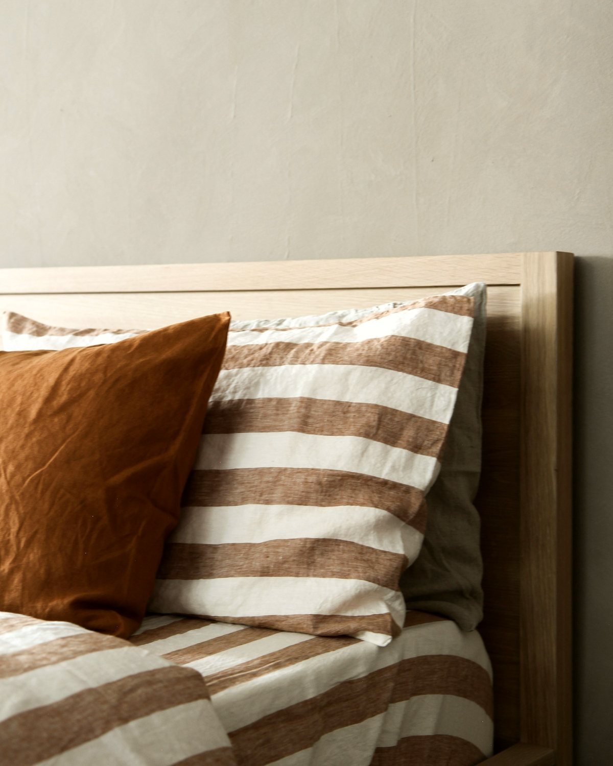 Washed linen bedding in rust and cream stripes on an oak bed